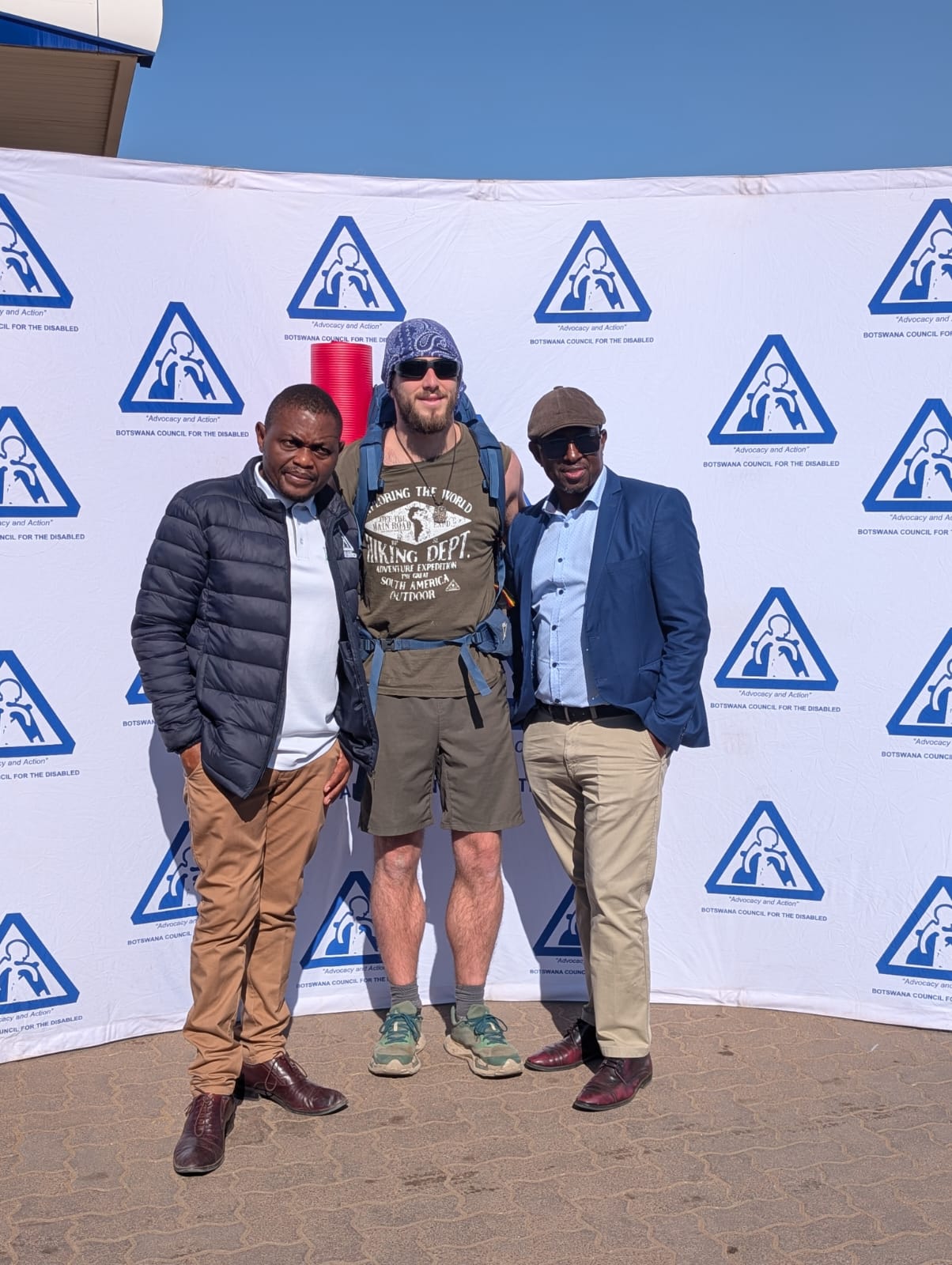 Three campaign supporters in front of a Botswana Council for the Disabled banner